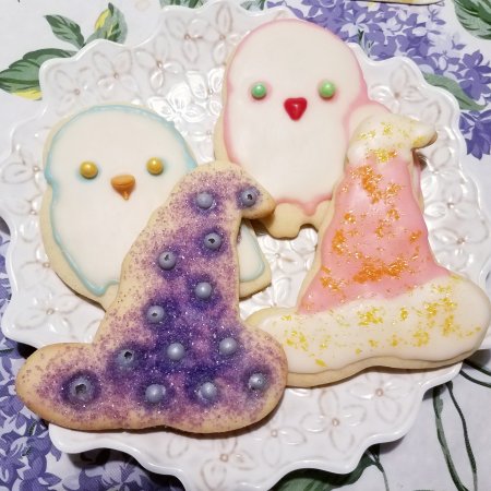Decorated owl and wizard hat cookies on a white plate.
